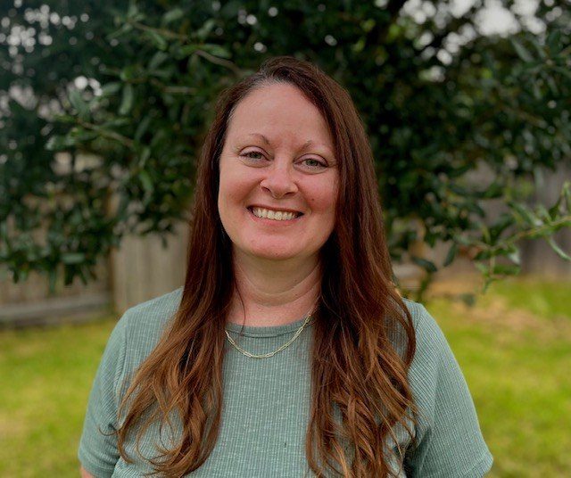 Kristina M. McGahan photographed outdoors in a sage-green top, smiling, with a live oak behind her.